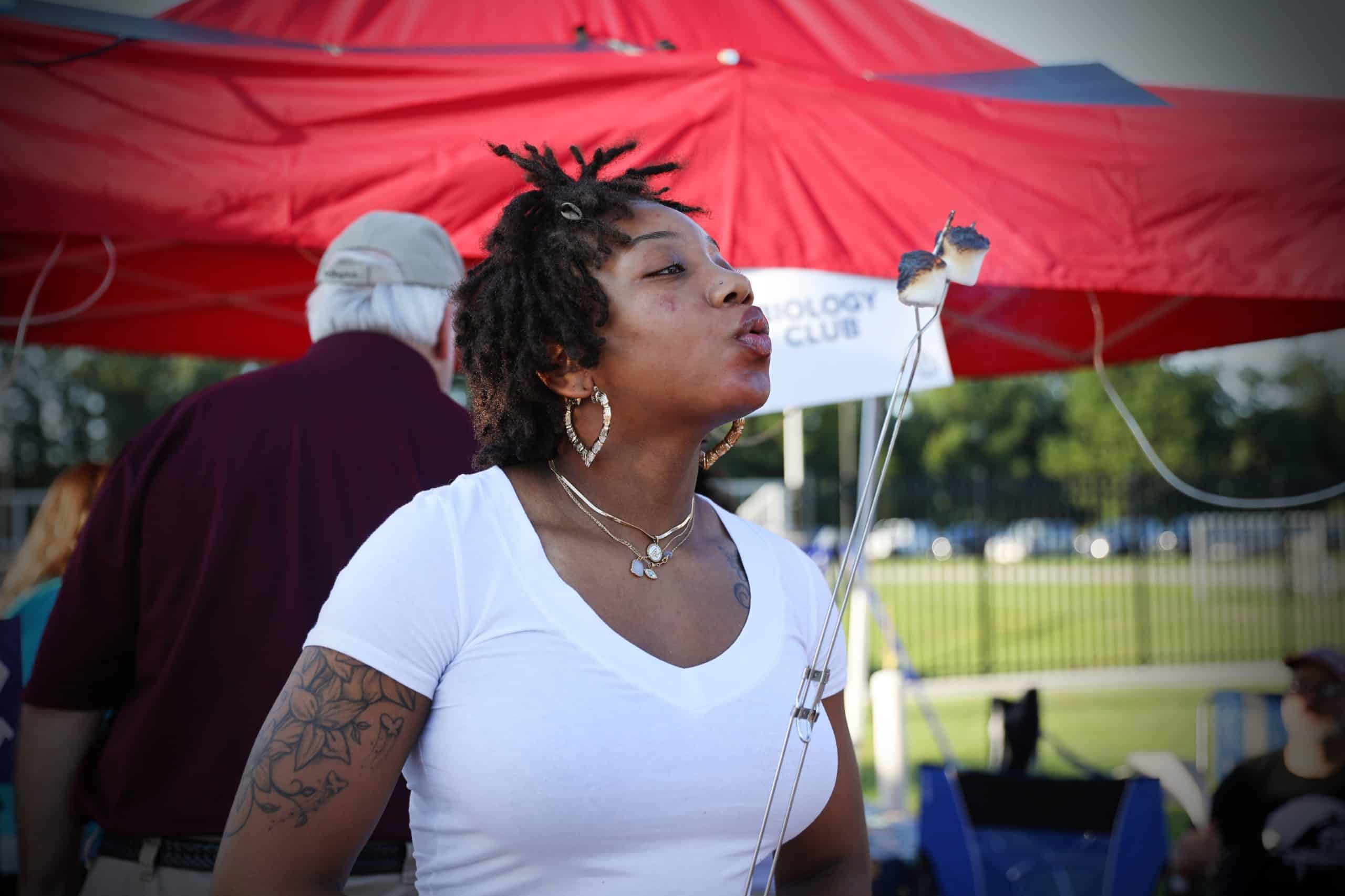 woman blowing out flaming marshmallow