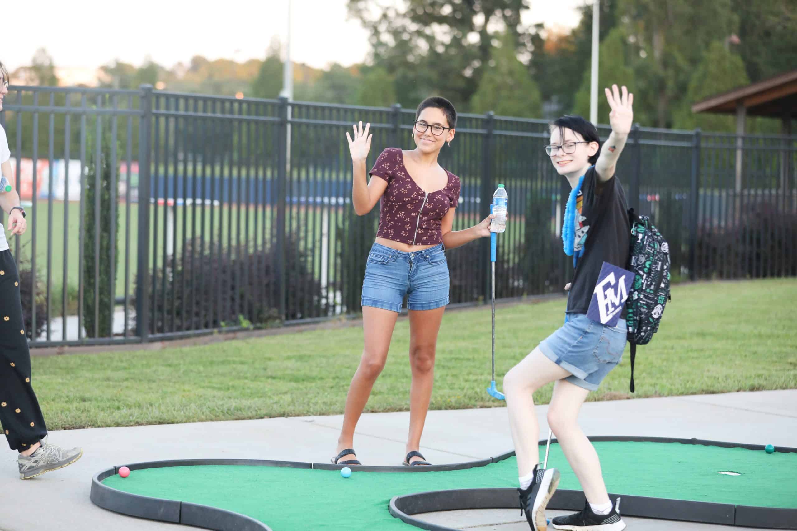 people smiling playing mini golf