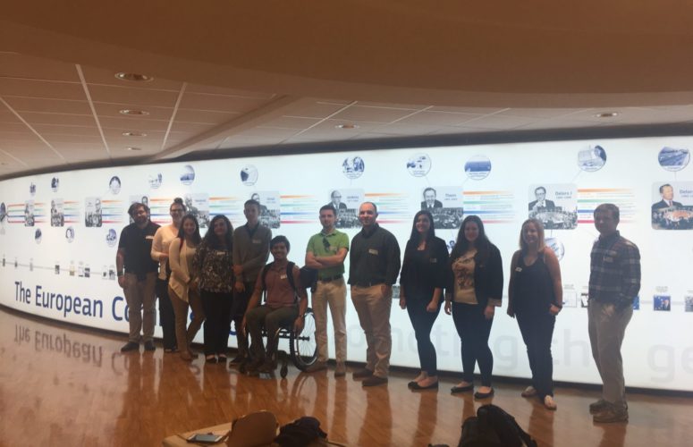 Students pose in front of the European Commission wall