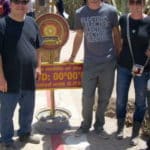 Three people posed with a sign