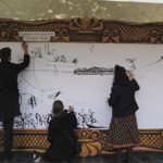 Three people drawing on a board