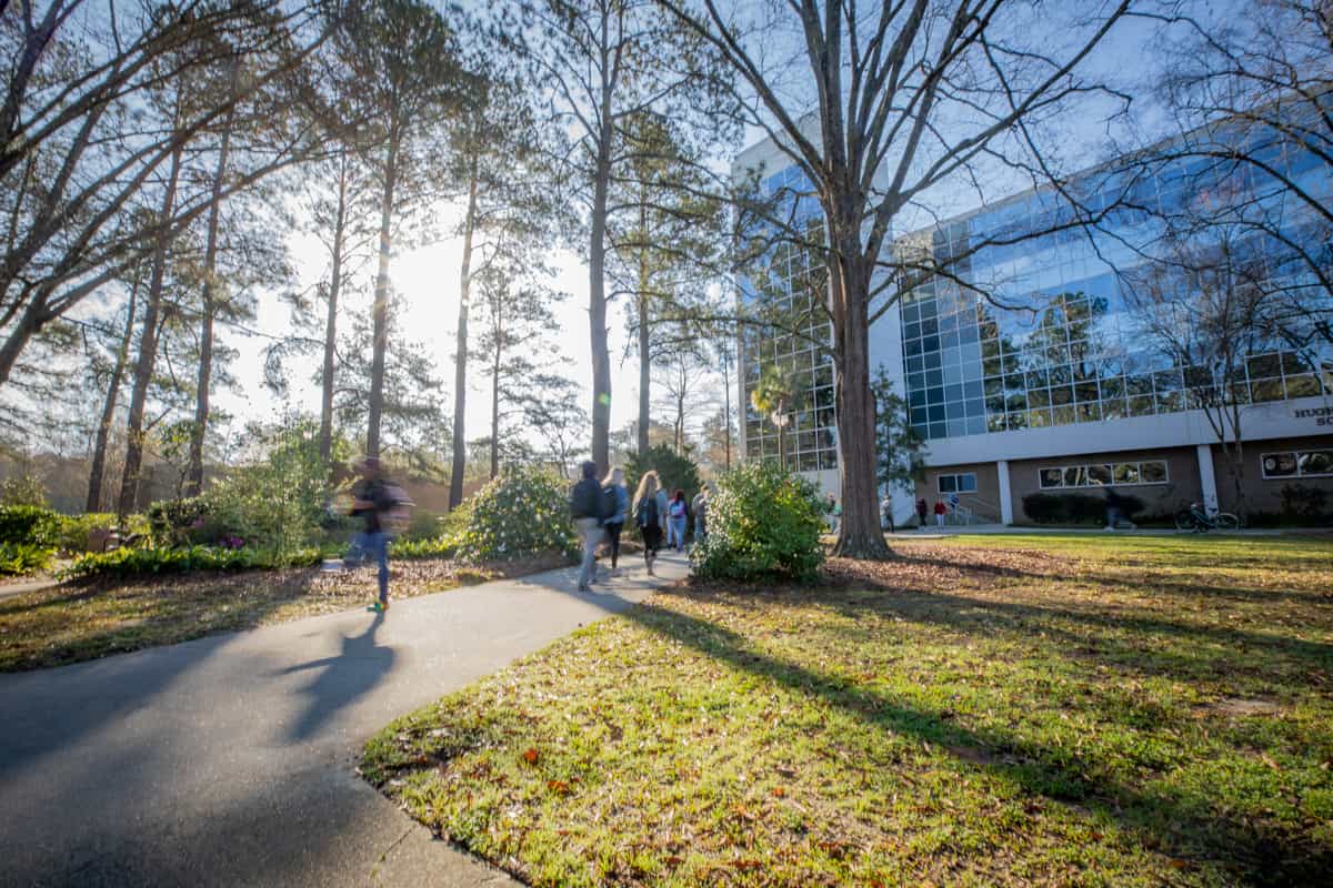 Students walk across FMU's campus on a sunny day.