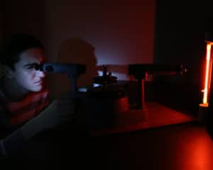 A student uses a tool to investigate a light in a dark room.