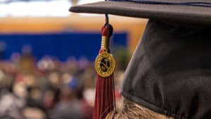 Close up of cap and tassel with commencement stage in background