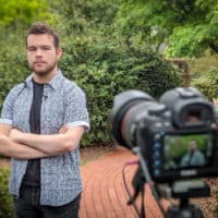 FMU graduate Garrett Fuller poses in front of a camera.