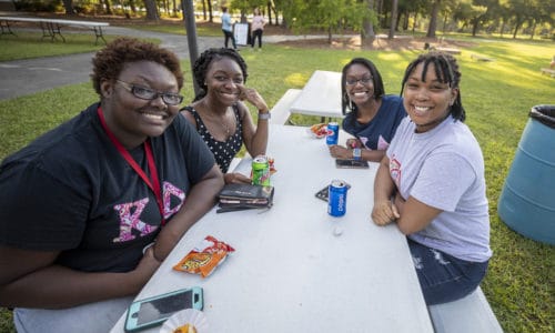 A group of friends pose for a picture during a cookout.