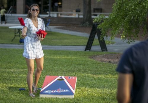 Two students play cornhole during a cookout on the UC lawn.