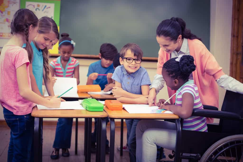 Pupils,And,Teacher,Working,At,Desk,Together,At,The,Elementary