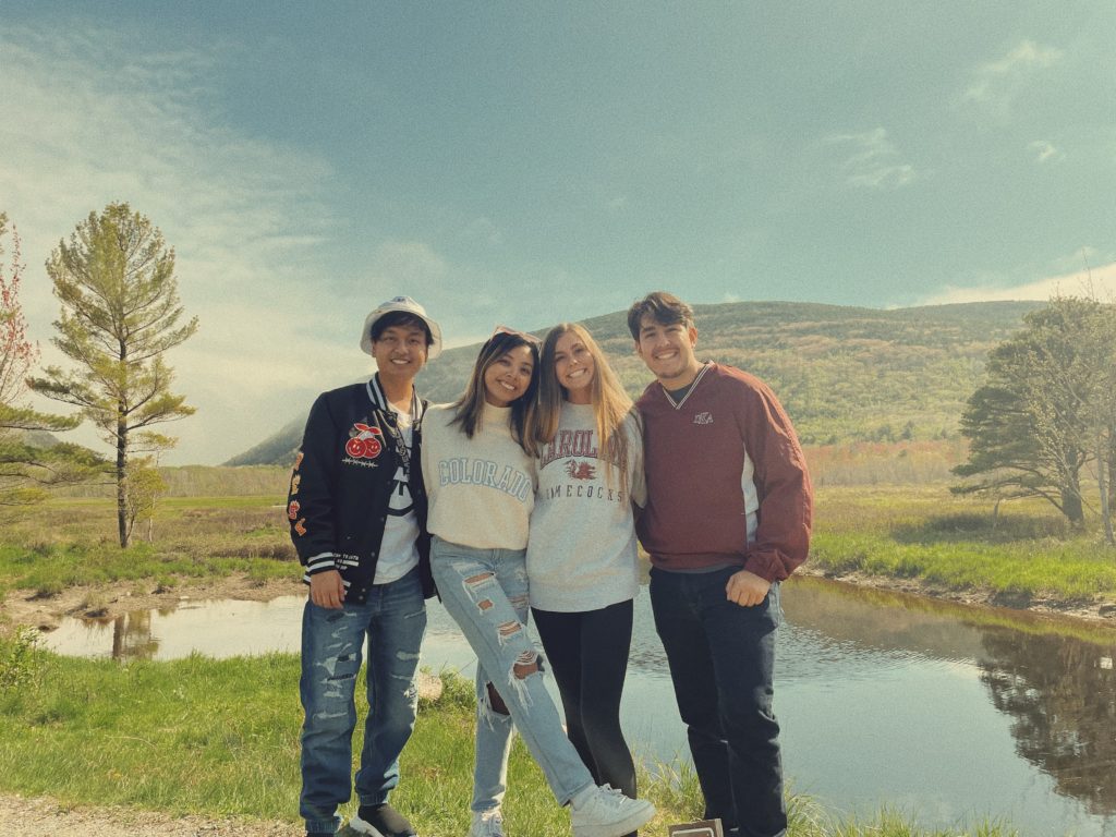 students standing and smiling in front of landscape