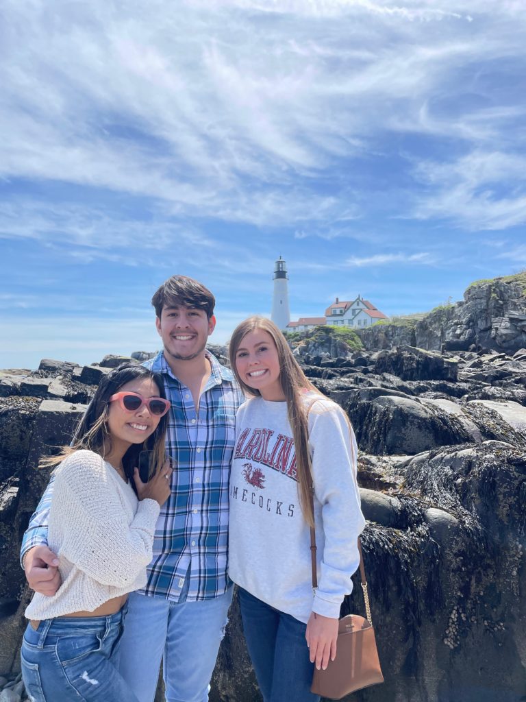 3 people posing in front of lighthouse