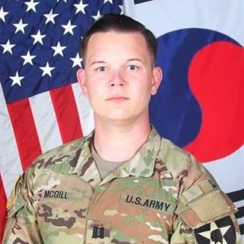 man standing in front of American flag in uniform